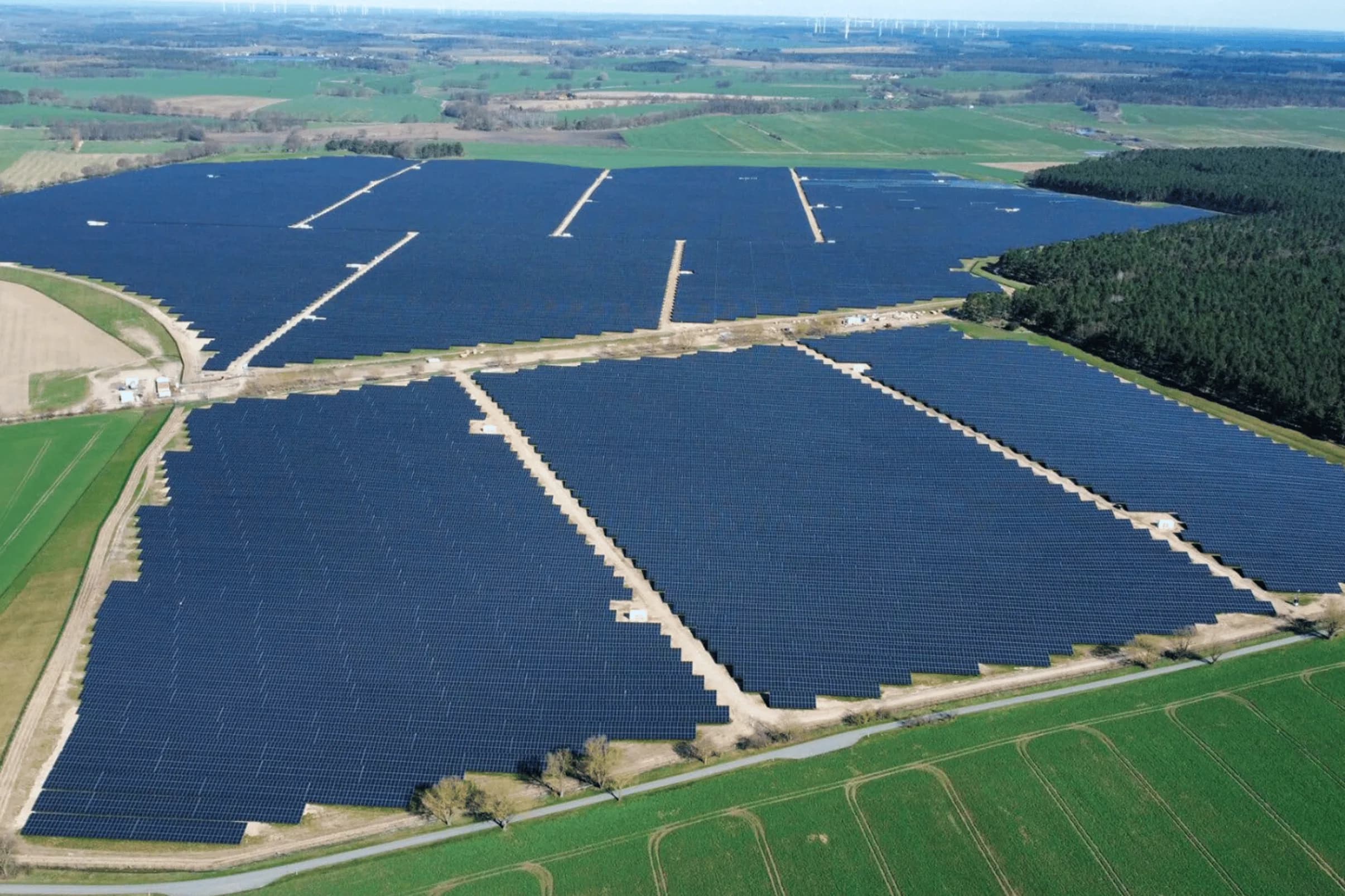 Rows of photovoltaic panels in a ground-mounted solar park, seen from above.
